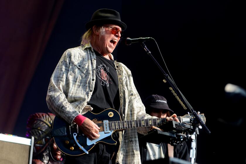 Neil Young playing guitar and singing into a microphone