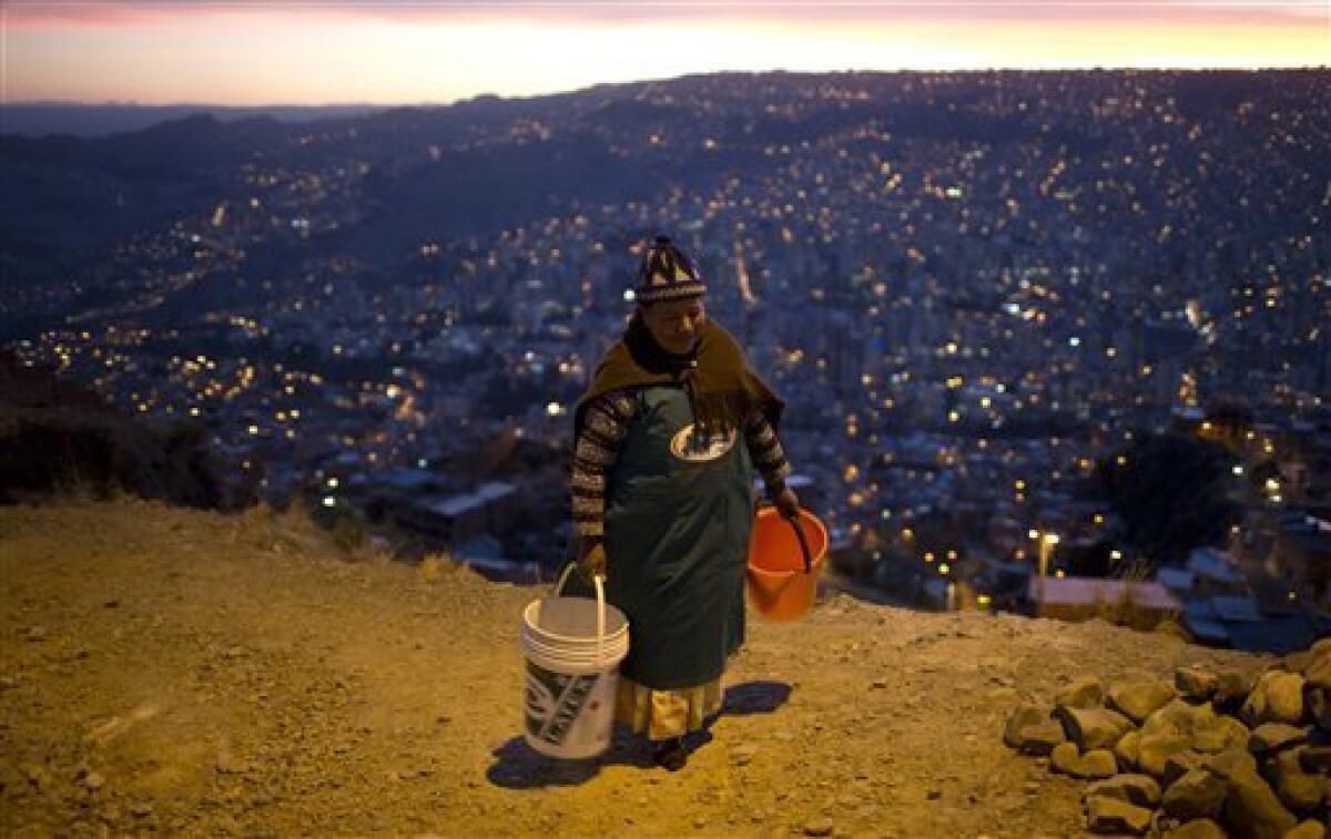 En esta imagen, tomada el 16 de noviembre de 2016, una mujer carga con dos baldes vacíos mientras espera la llegada de un camión cisterna con agua a cerca de su vecindario en La Paz, Bolivia. El presidente del país, Evo Morales, pidió perdón a los residentes de La Paz por la escasez de agua provocada por la peor sequía en 25 años y reconoció que no hay una solución inmediata al problema.