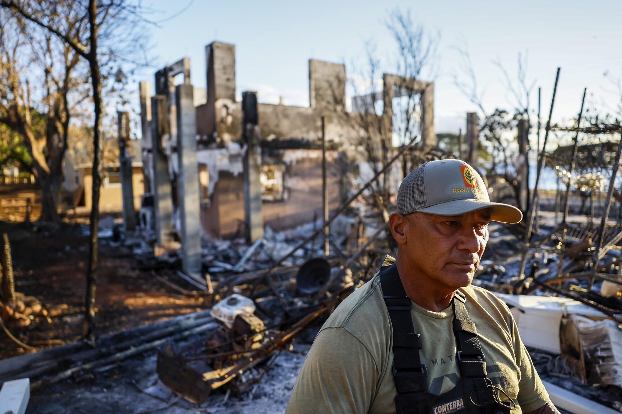 Archie Kalepa stands in front of a home destroyed by fire.