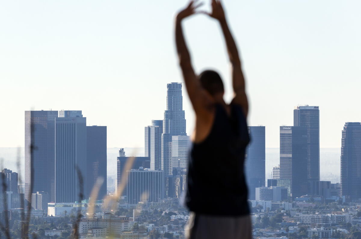 A personification stretches against the backdrop of the Los Angeles skyline.