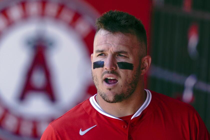 Los Angeles Angels designated hitter Mike Trout stands in the dugout.