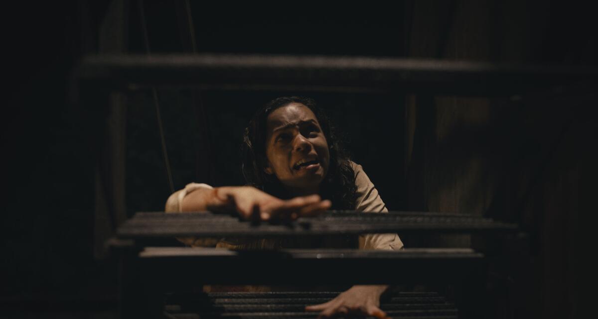 A distressed woman attempting to climb a ladder in the dark