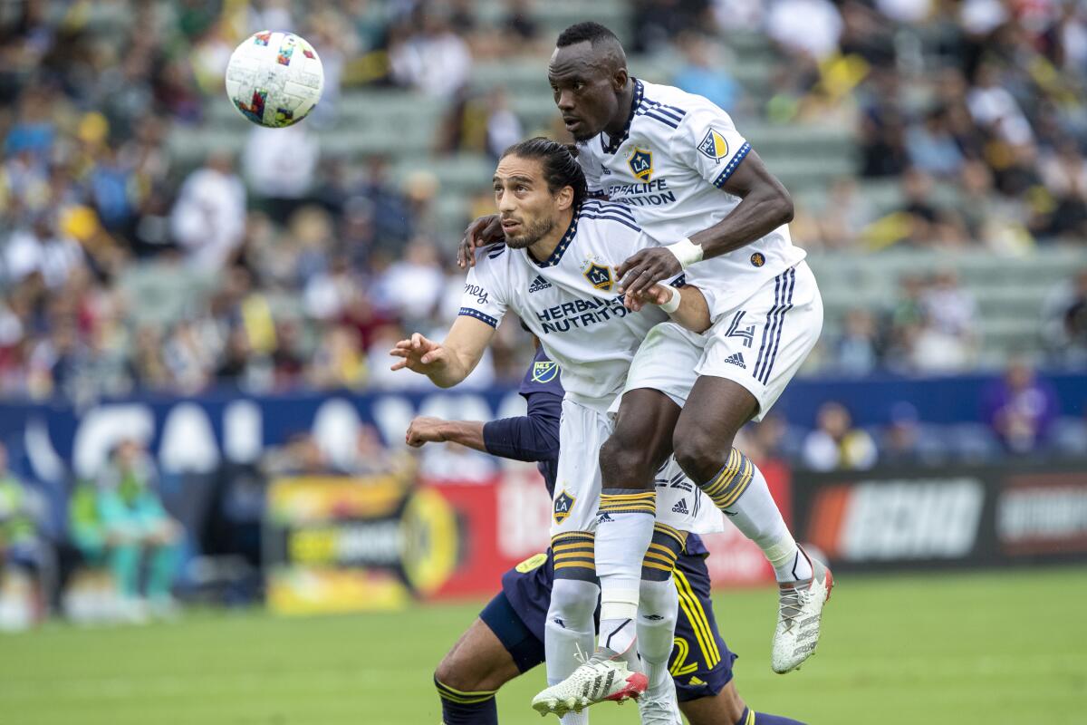LA Galaxy defender Martin Caceres, left, and defender Sega Coulibaly, right, head the ball away.