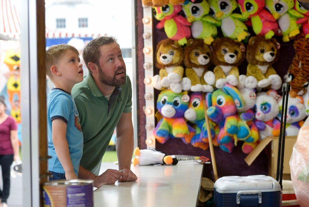 Michael Hickey of Union Bridge and his son Asher, 4, peruse the prizes in a dart game on the midway of the Union Bridge fire company carnival Tuesday, May 28, 2019.