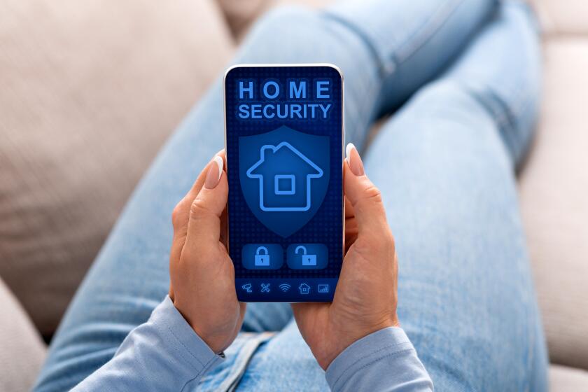 Smart house, home automation, device with app icons. Over the shoulder view of woman using her smartphone with home security application on the screen to unlock the door of the house