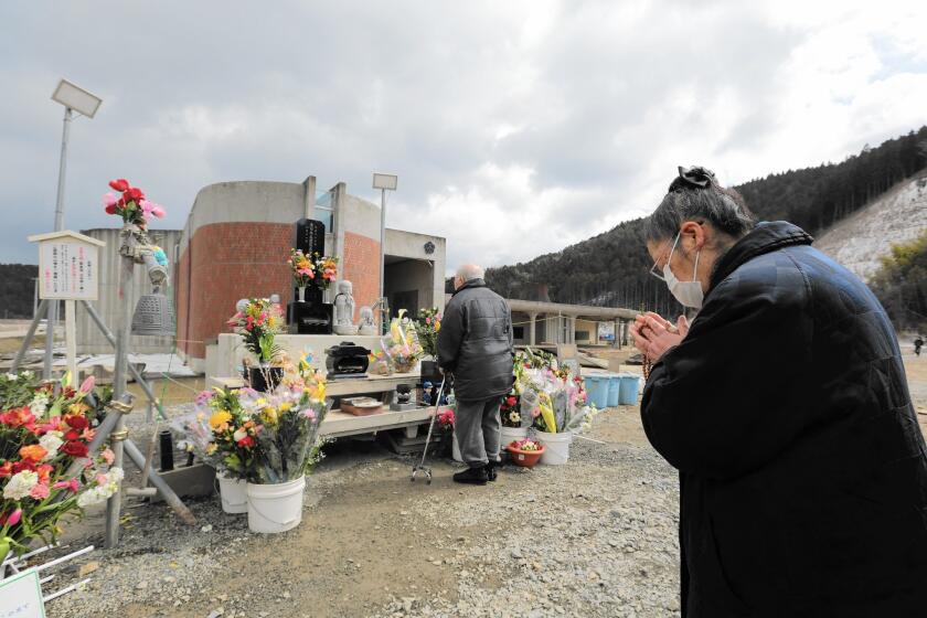 A woman offers prayers at Okawa Elementary School in Japan on the third anniversary of the March 11, 2011, earthquake and tsunami. Seventy-four of the school's 108 students died in the disaster.