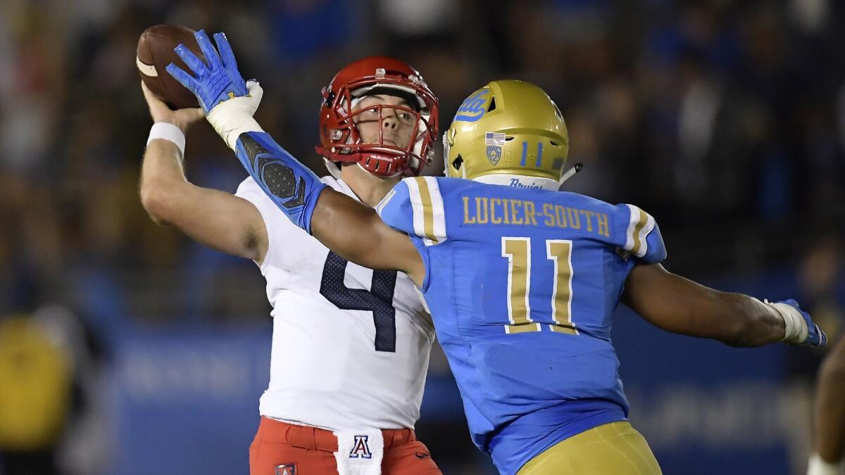 Arizona quarterback Rhett Rodriguez, left, passes while under pressure from UCLA linebacker Keisean Lucier-South.