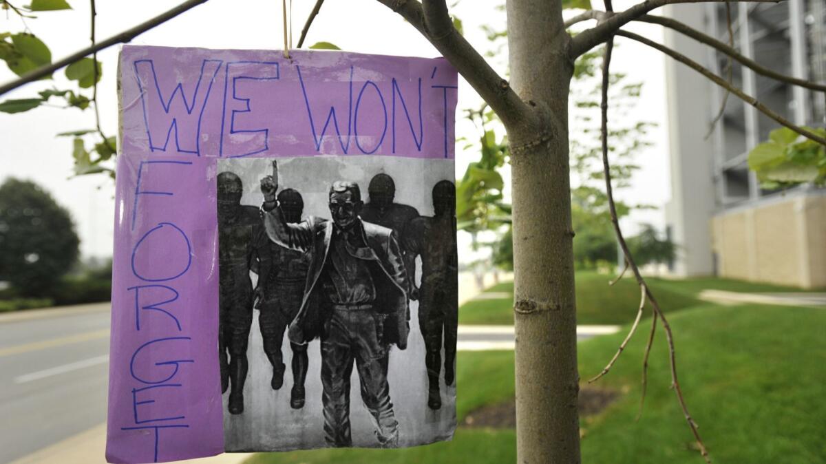 A sign reading "We won't forget" hangs from a tree at the site where former Penn State college football coach Joe Paterno's statue once stood in State College, Pa. on July 22, 2013.