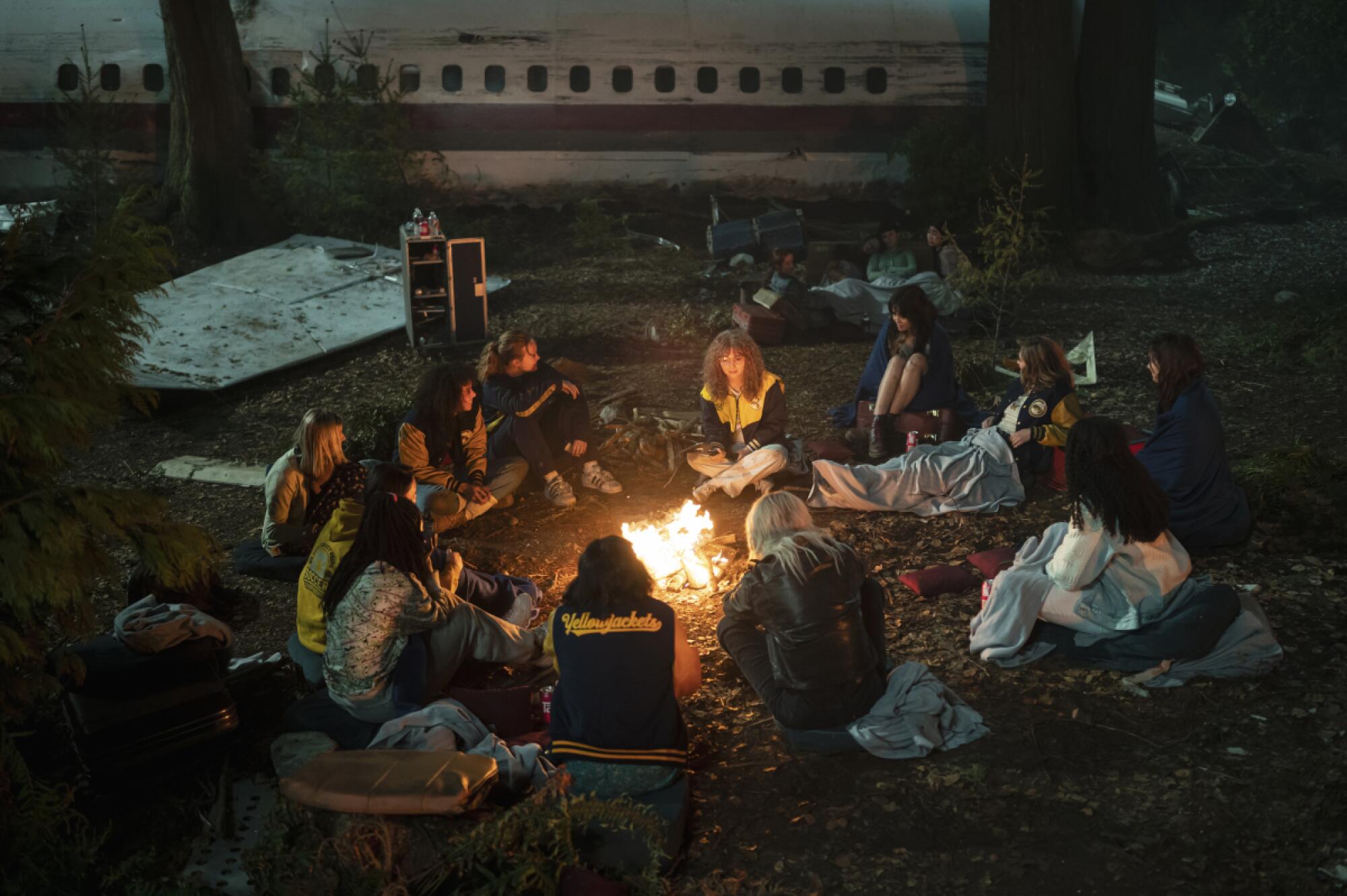The teenage survivors of a plane crash sit around a fire in the wilderness in "Yellowjackets."