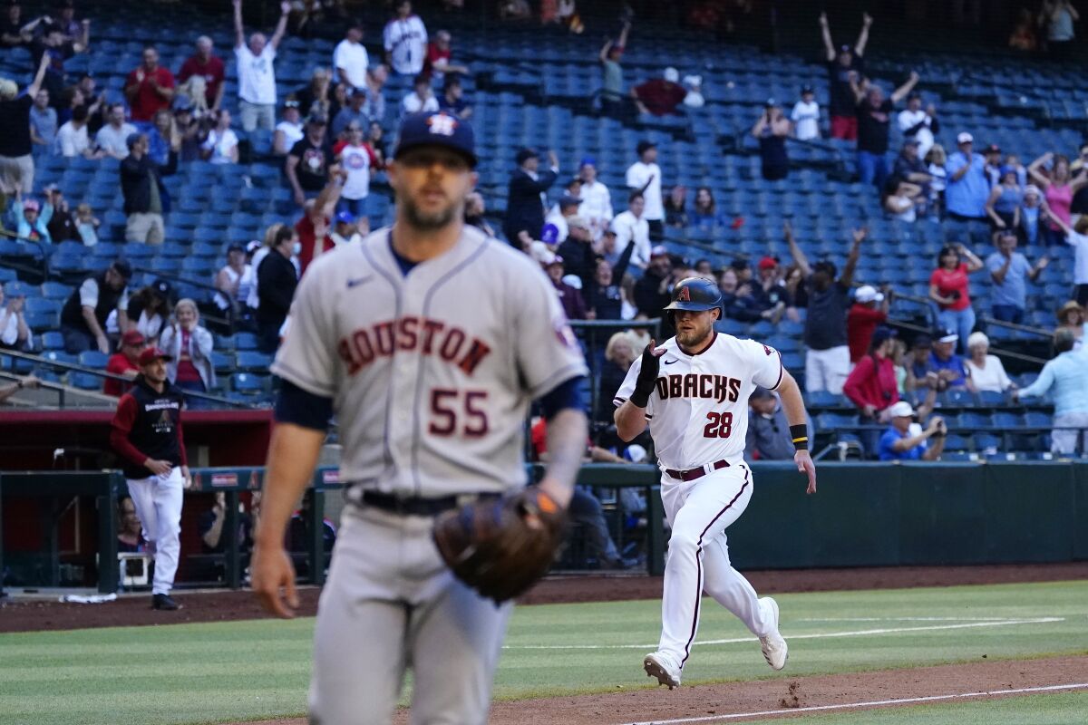 Arizona Diamondbacks' Seth Beer (28) heads home with the winning run as Houston Astros relief pitcher Ryan Pressly (55) walks off the field during the 10th inning of a baseball game Wednesday, April 13, 2022, in Phoenix. The Diamondbacks won 3-2. (AP Photo/Ross D. Franklin)