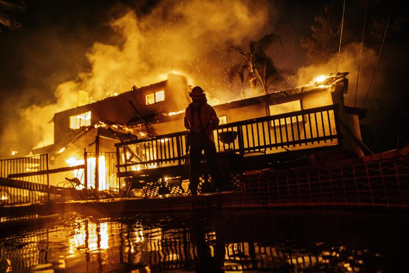 Photographs by Marcus Yam  Los Angeles Times FIREFIGHTERS WORK to control the spread of the Hillside fire early Thursday as a home burns in San Bernardino. Across the state, more than 100 structures have been destroyed in dozens of fires in the last week.