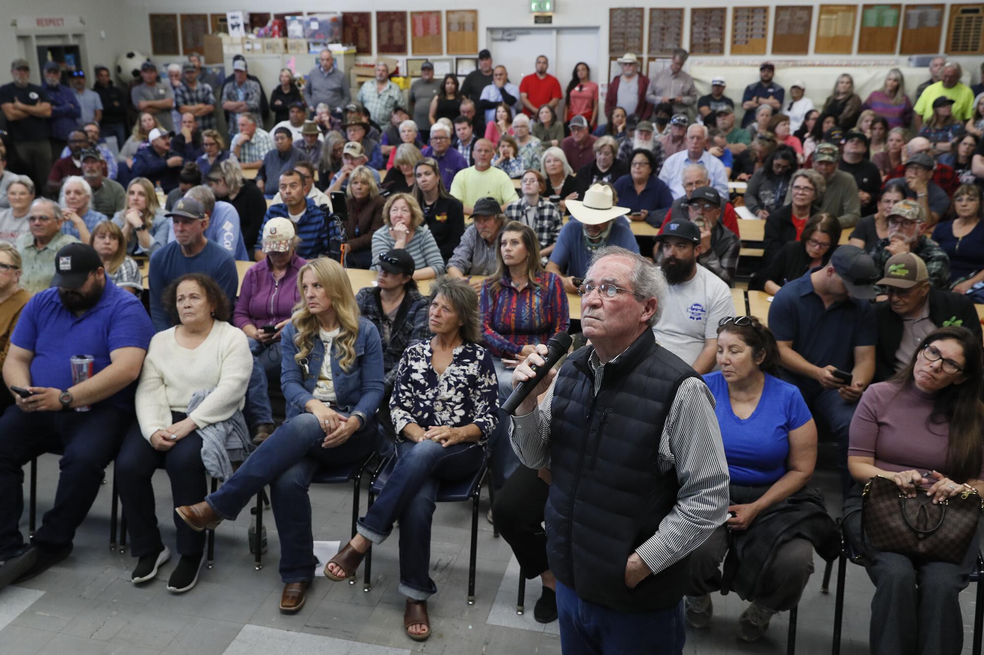 Dozens of people sit in an auditorium listening to a speaker.