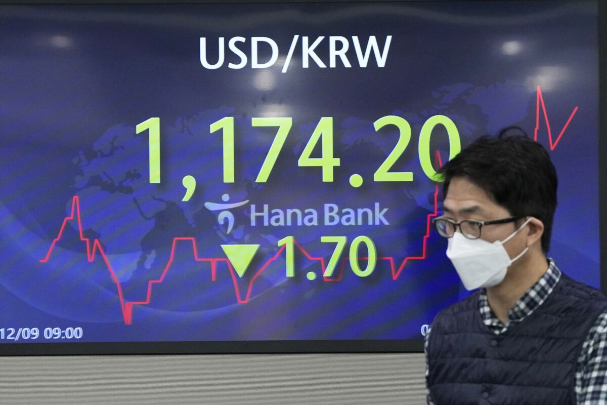 A currency trader walks by a screen showing the foreign exchange rate between U.S. dollar and South Korean won at a foreign exchange dealing room in Seoul, South Korea, Thursday, Dec. 9, 2021. (AP Photo/Lee Jin-man)