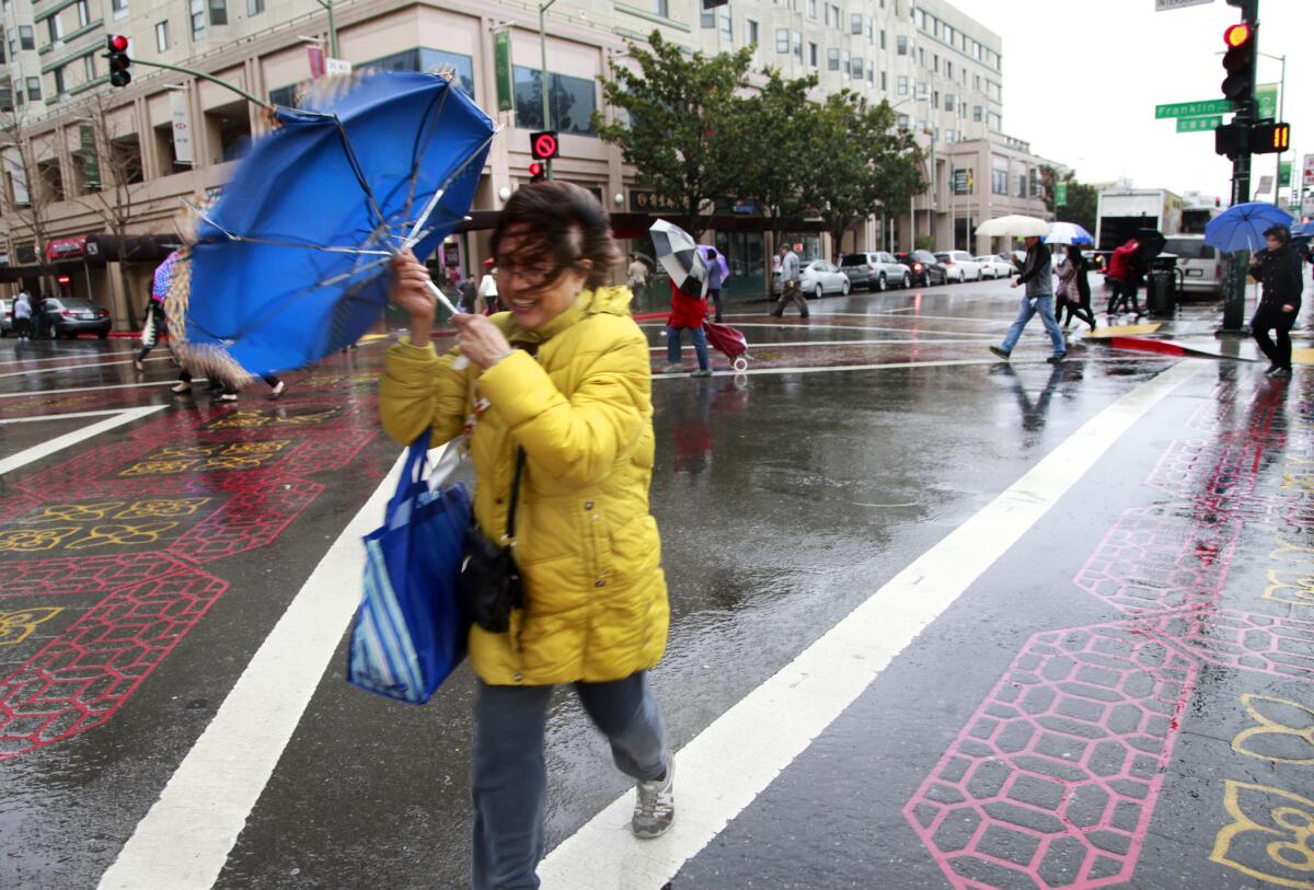 Pedestrians in Oakland's Chinatown battle the wind and rain as they cross at Franklin and 9th streets on Feb. 6, 2015. The Asian population in Alameda County, where Oakland is located, has surpassed the white population, census data show.