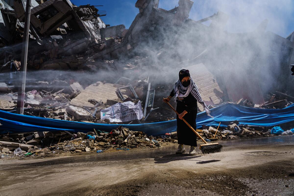 A woman sweeps at the site of a destroyed tower.