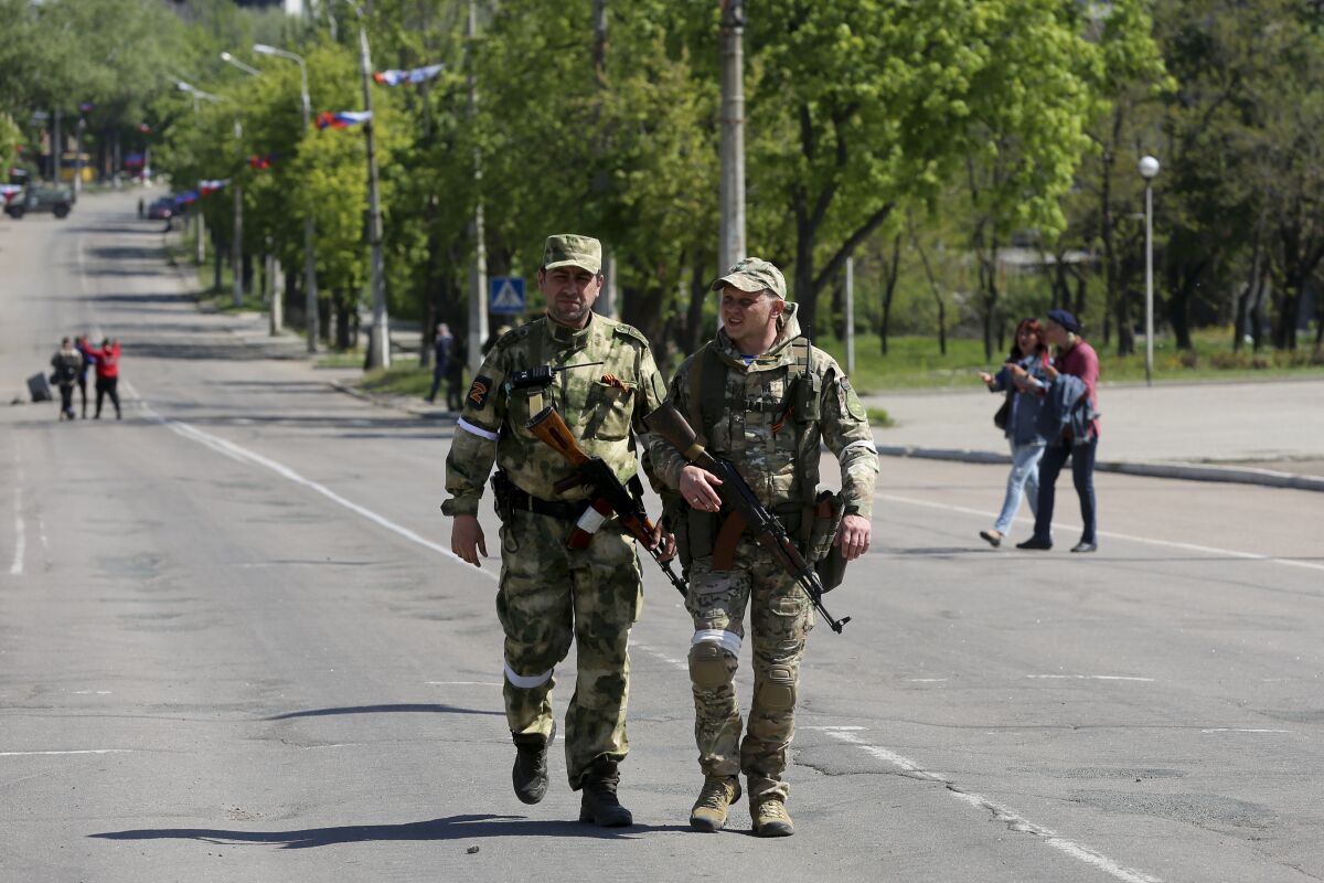 Pro-Russia militiamen patrol a street in Mariupol, Ukraine.