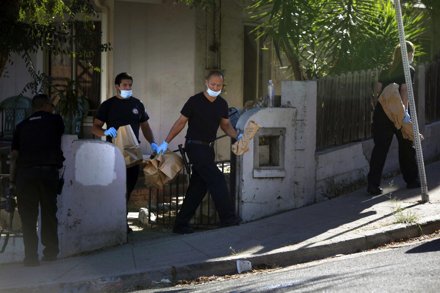 Police carry items away from a residence in the 4400 block of Topaz Street in Montecito Heights. Police served a series of search warrants in November in the neighborhood and detained some people for questioning as they continued investigating the deaths of two teenagers whose bodies were found in a park.
