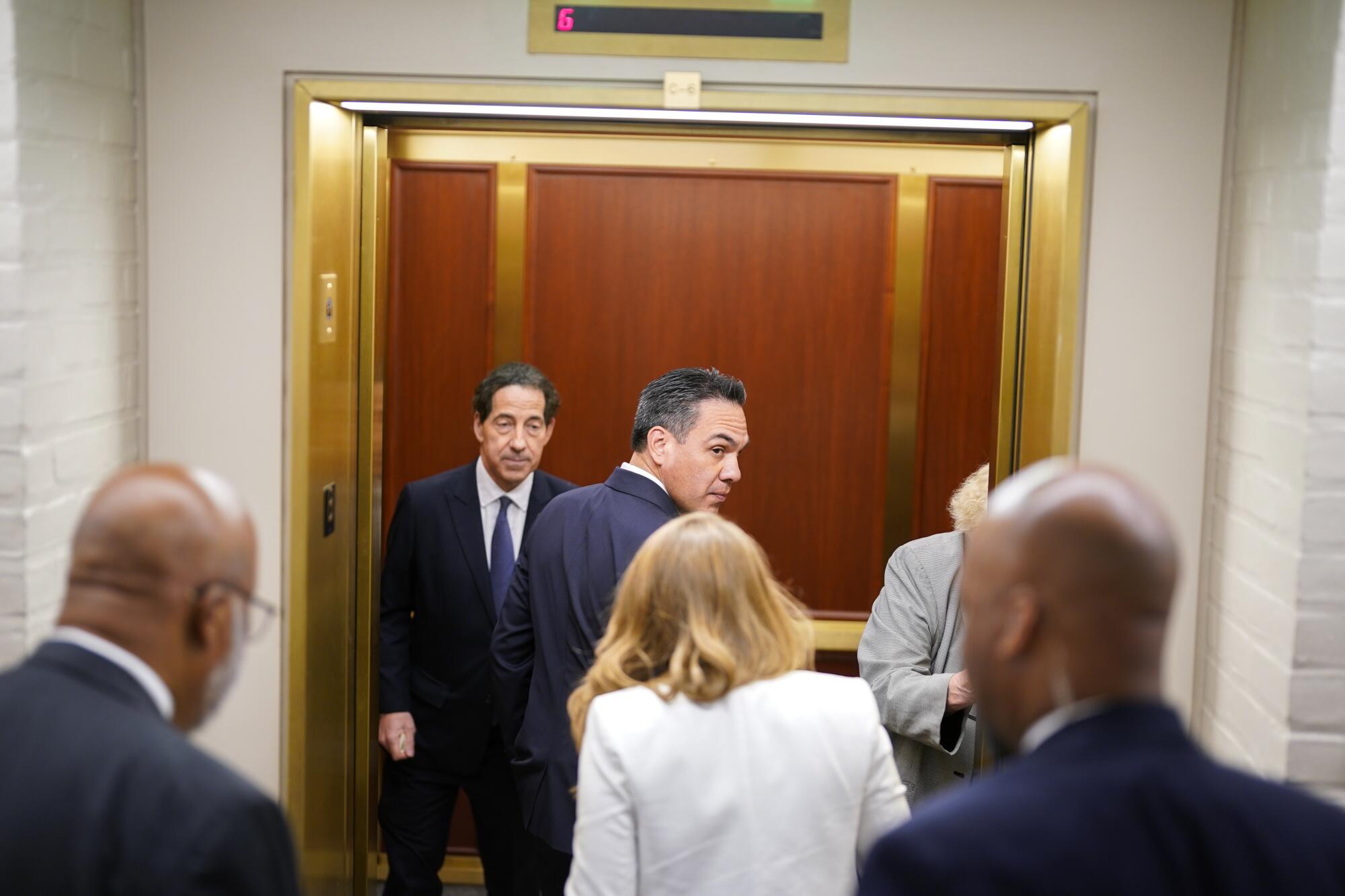 Pete Aguilar, center, and Jamie Raskin, second left, walk into an elevator followed by several other people seen from back