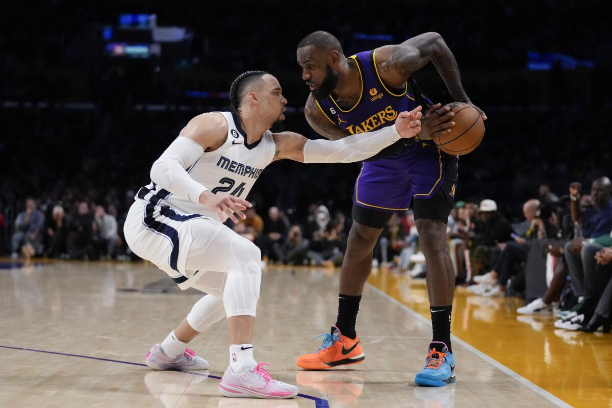 Grizzlies forward Dillon Brooks, left, takes a swipe at the ball as Lakers forward LeBron James looks to drive.
