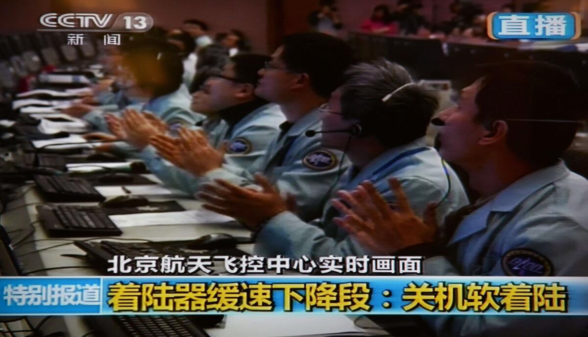 This screen grab taken from CCTV live broadcasting footage shows scientists celebrating at the control center in Beijing after China's first lunar rover landed on the moon on Saturday.