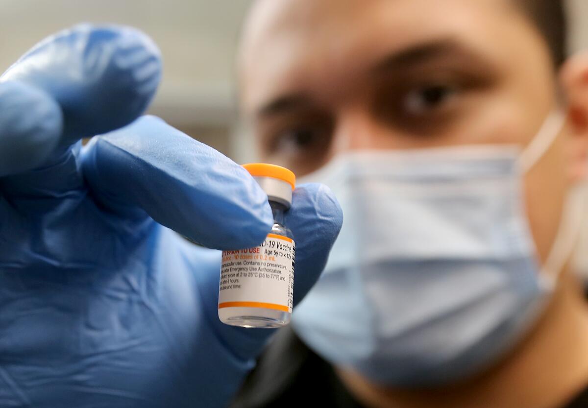 Nurse Luis Garcia holds a vial of the Pfizer vaccine at Hellen Keller Elementary School in Lynwood.