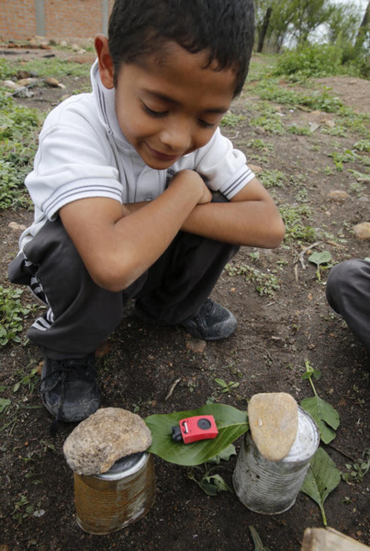 Marcos Ireta admires the tiny green leaf hammock he crafted with rusty cans and rocks outside his house near Irapuato, Mexico. With little money available for ready-made toys, he and his five siblings make do with imaginary games and toys.