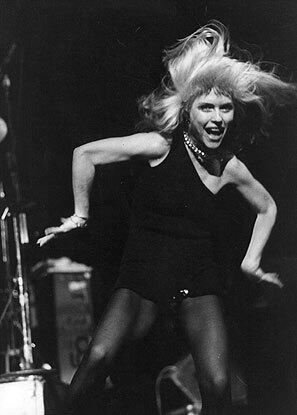 When pioneering new wave band Blondie made the leap from New Yorks art-rock scene to the wide world, lead singer Debbie Harrys look went from scrappy to sultry. The underground accused the band of selling out, but Harrys solid-colored, one-shouldered disco dresses proved that uptown chic could coexist with downtown cool. The slinky look remains one of fashions most referenced.