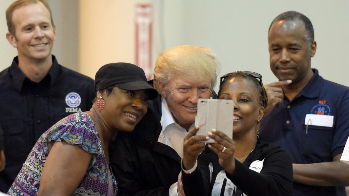 President Trump gets a selfie with flood evacuees at NRG Stadium in Houston, joined by FEMA Director Brock Long, left, and HUD Secretary Ben Carson.