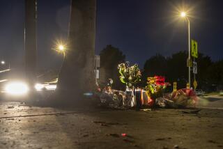 LOS ANGELES, CA - DECEMBER 12, 2021: Flowers and candles have been placed at the scene where a USC student was struck and killed by a motorist as he was walking home with groceries Saturday afternoon at the intersection of Jefferson and Harvard Boulevards on December 12, 2021 in Los Angeles, California. Two motorists have been detained by police. (Gina Ferazzi / Los Angeles Times)