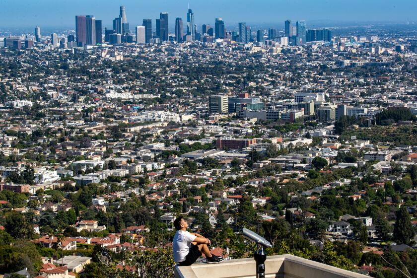 Los Angeles, CA - June 21: Billy Enkhbat, of Los Angeles, takes in some sun and a view of downtown while sitting on a ledge at the Griffith Observatory on Wednesday, June 21, 2023 in Los Angeles, CA. (Brian van der Brug / Los Angeles Times)