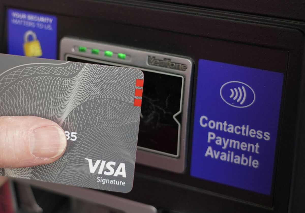 A customer uses the contactless payment chip in this VISA card to purchase gasoline at a gas station in Ridgeland, Miss., Thursday, July 1, 2021. Visa says it will lower its credit card “swipe” fees for online and in-store transactions by 10% for small businesses starting in April 2022. The move comes as the digital payments sector becomes increasingly competitive. (AP Photo/Rogelio V. Solis)