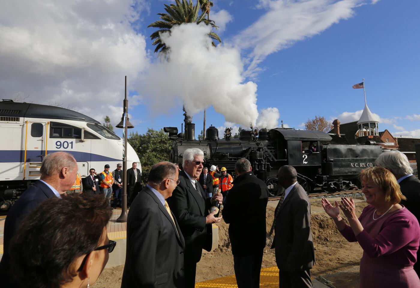 Local and federal officials cheer as a 1922 steam locomotive from the Orange Empire Railway Museum blows its horn during the dedication ceremony of the new Perris route set to open early next year.