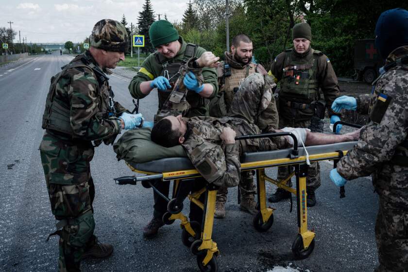 Medics attend to a wounded Ukrainian soldier on stretcher in the middle of a road.