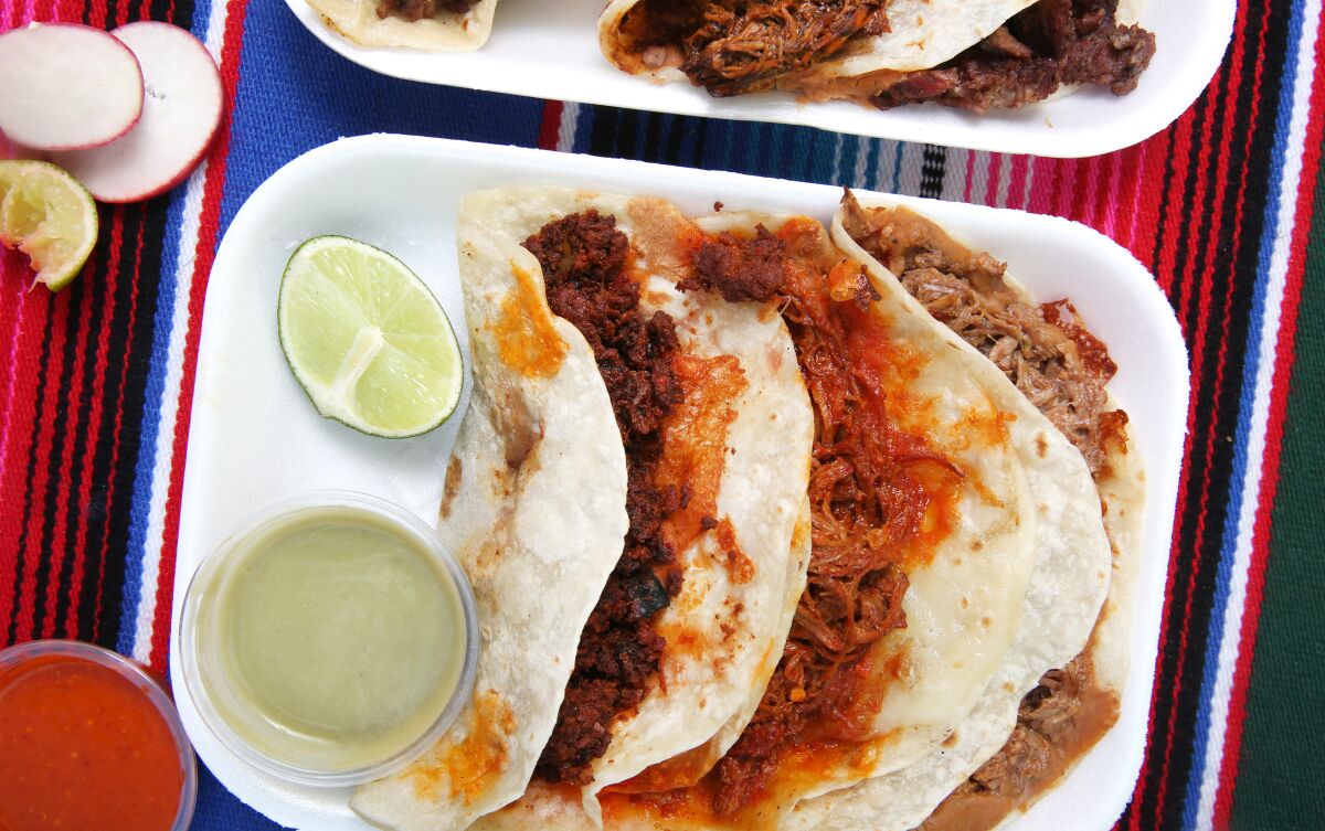 Three kinds of tacos on a plate with a lime slice