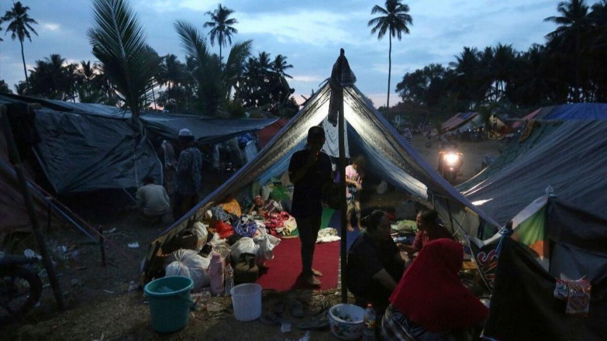 Villagers gather at a temporary shelter after fleeing their damaged village following Sunday's earthquake in North Lombok, Indonesia