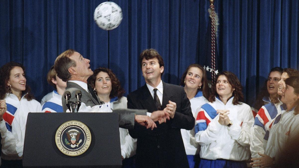 President George H.W. Bush heads a soccer ball while meeting members of the 1991 U.S. women's soccer team, which won the inaugural tournament that is now known as the Women's World Cup.
