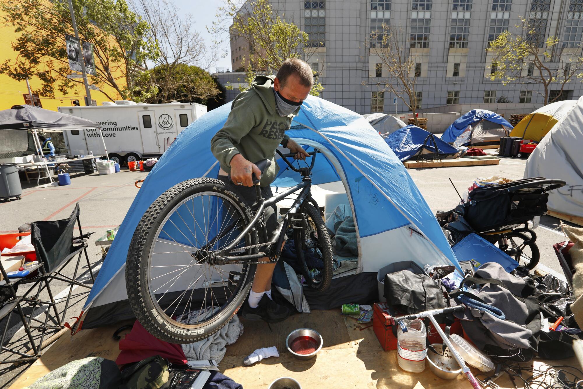 A man carries a bike outside a tent