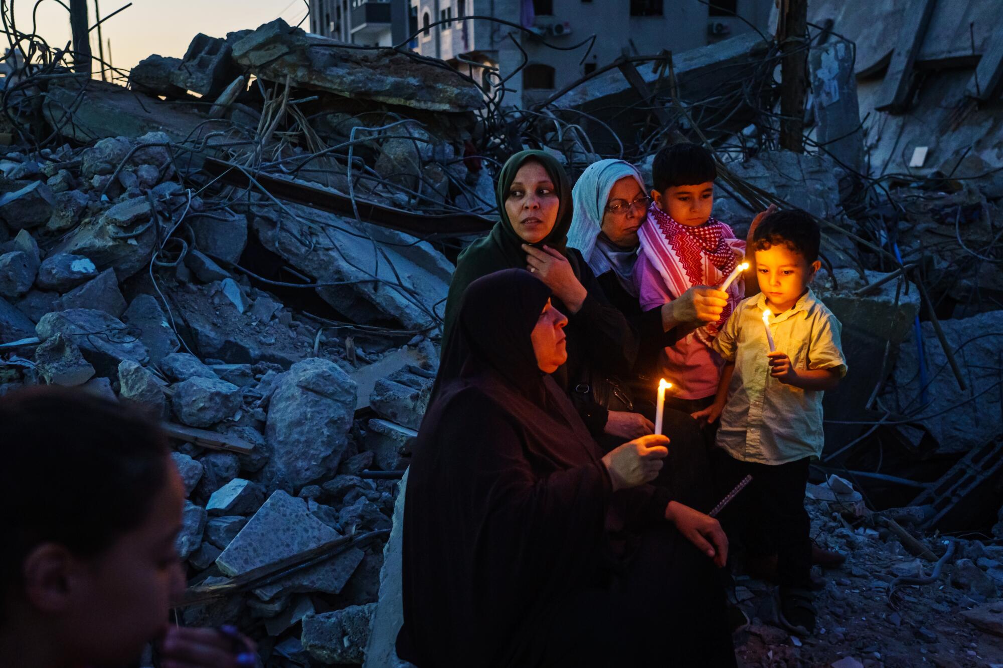A small group of women and children hold candles at a vigil in Gaza City.