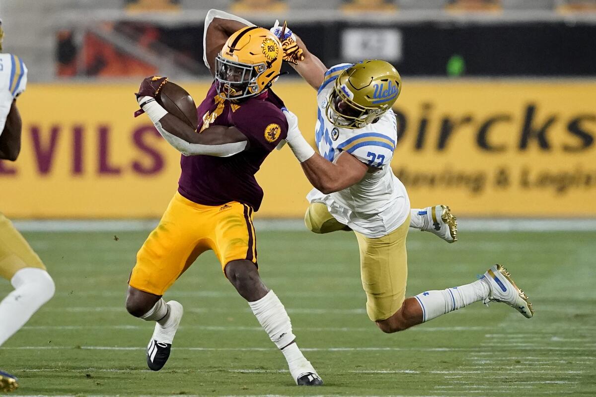 Arizona State running back Rachaad White, left, is tackled by UCLA linebacker Bo Calvert