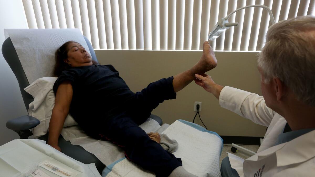 Dr. Stanley Mathis examines Maria Valdez, a diabetic who underwent surgery to save her foot when it became infected so she could avoid amputation.