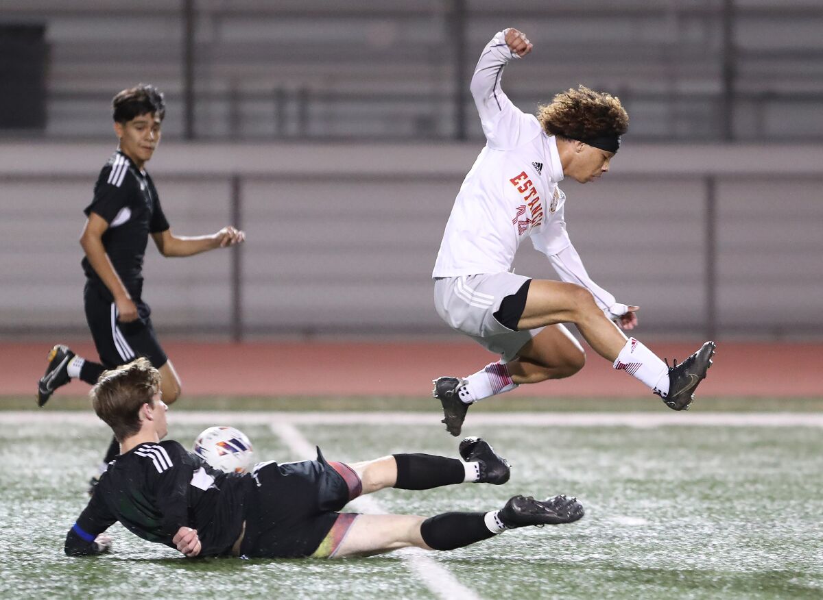 Estancia's Brandon Garcia is slide tackled by Costa Mesa's Aidan Markert during the Battle for the Bell boys' soccer match.
