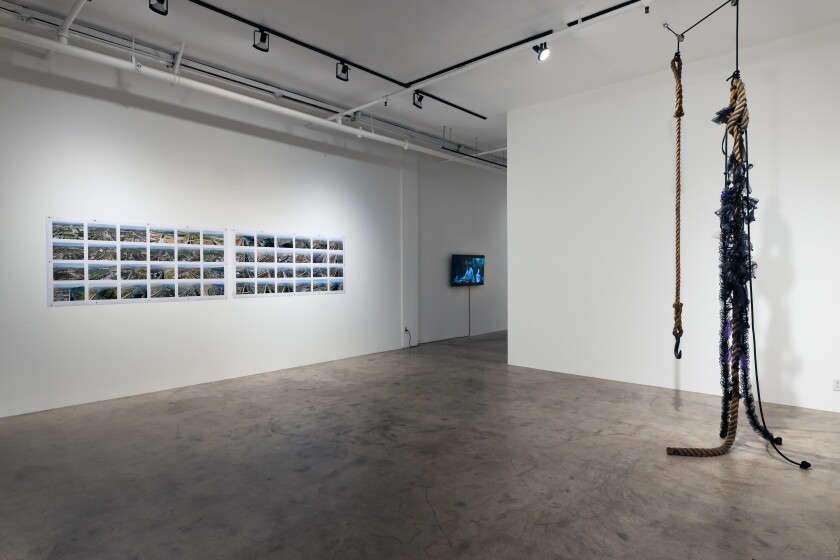 Installation view of photographs, video and a hanging sculpture.
