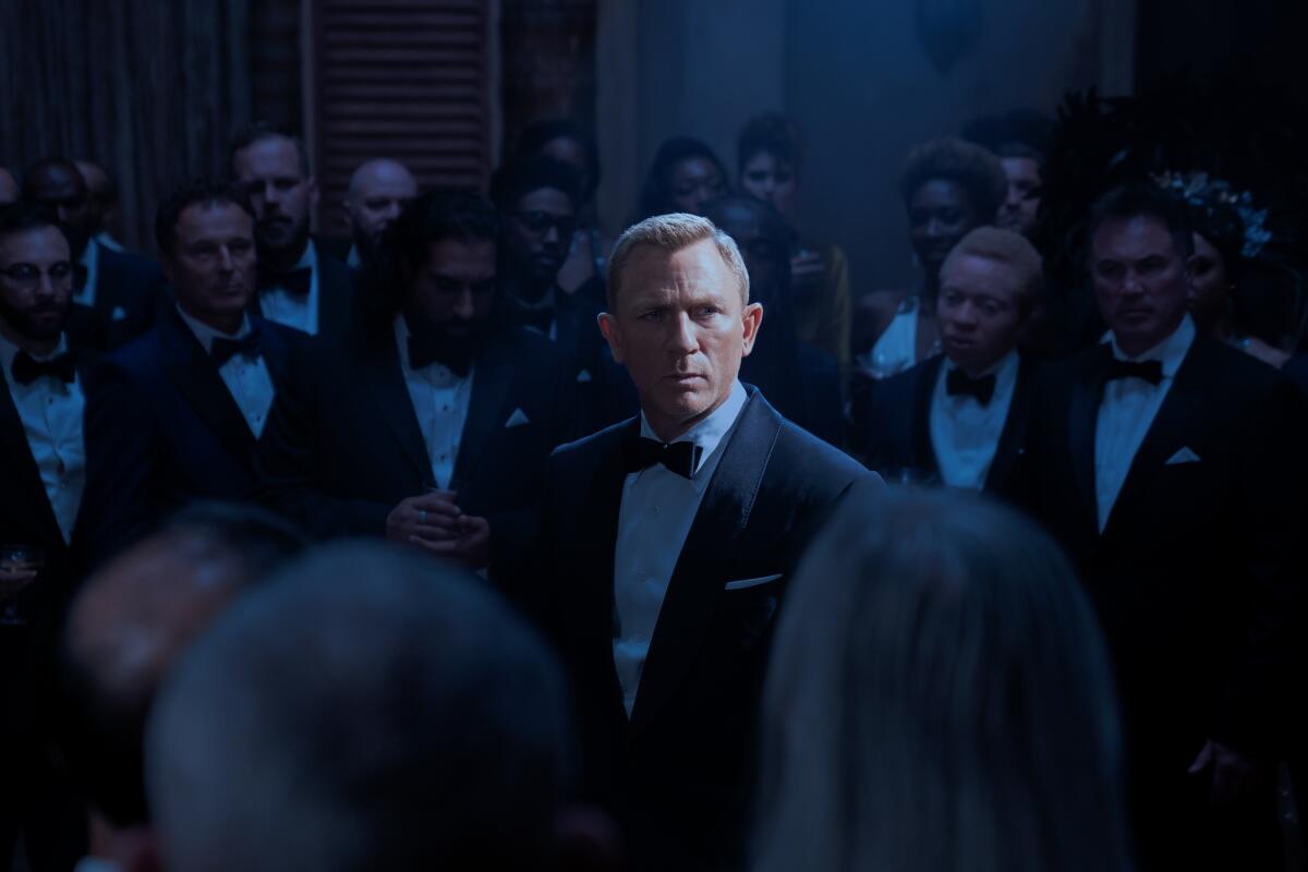 A man in a tux in a dark room filled with other men in tuxes