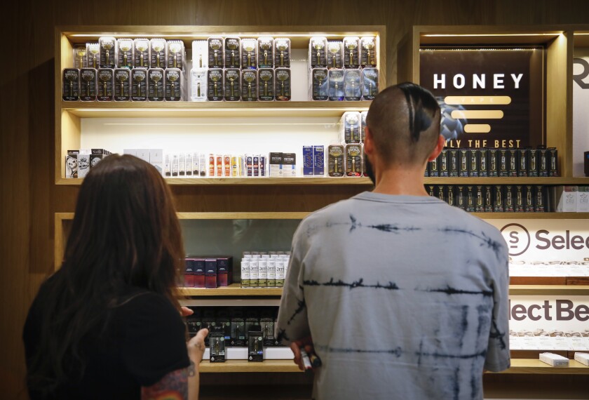 Tina Glen, left, and Nick Isordia, right, look at some of the the vaping products at March and Ash, a legal cannabis dispensary in Mission Valley. Sales of vaping products have been down in recent weeks due to concerns over lung illnesses.