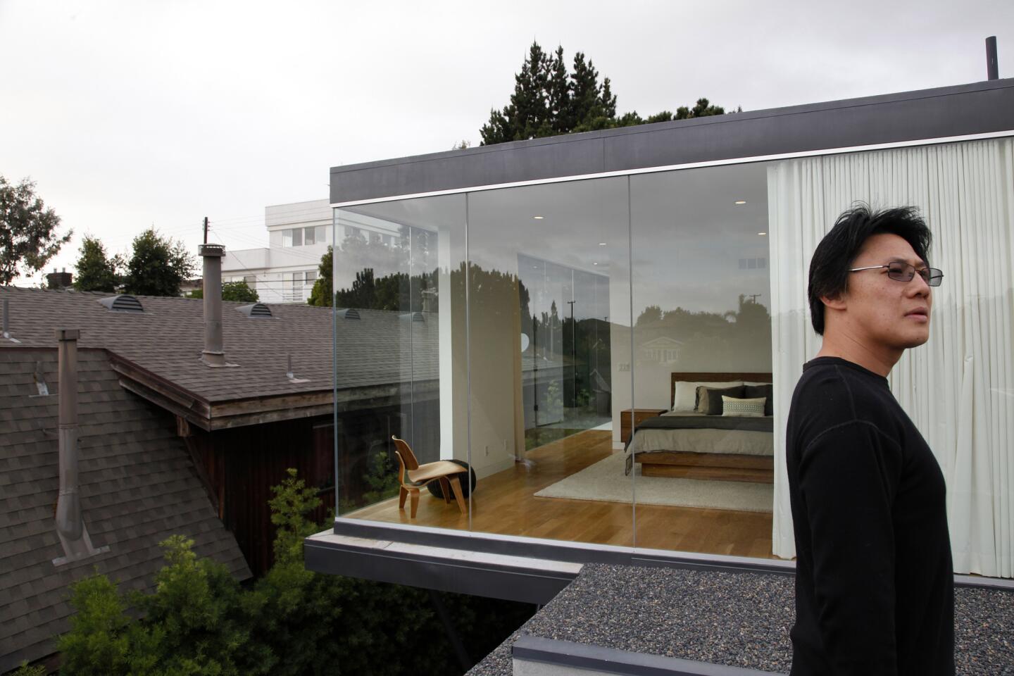 After architect Kevin Tsai was forced to sell the Playa del Rey home he had designed for himself and his family, he re-imagined it -- for Max and Sonia Kim and their two children. Here, Tsai stands on the roof of the original home, facing the glass-box addition he designed.
