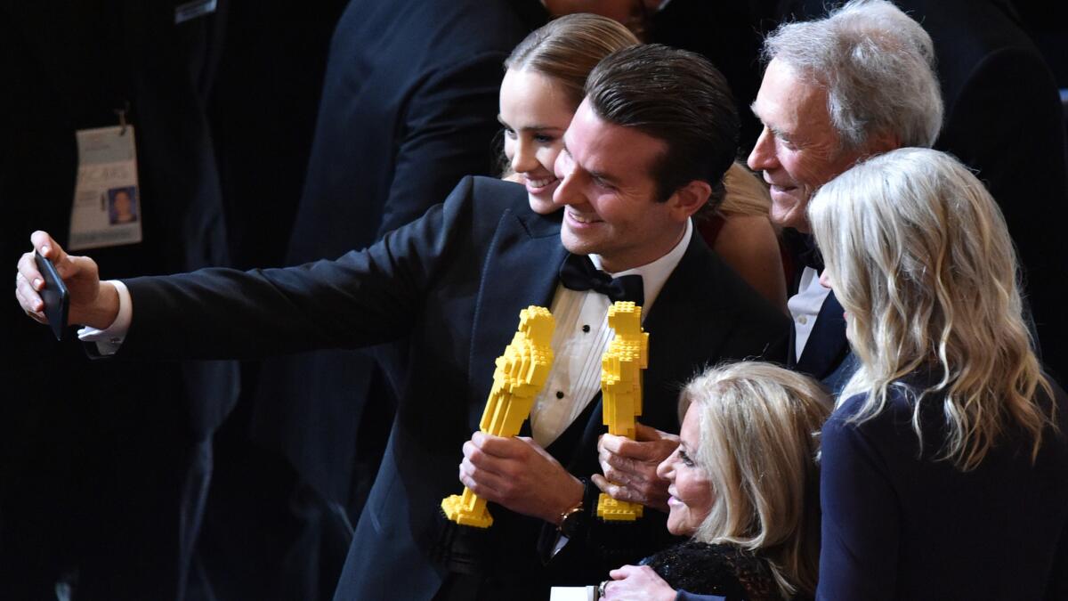 Model Suki Waterhouse, left, actor Bradley Cooper and director Clint Eastwood pause for a selfie with Oscars made of Legos at the Academy Awards in February.