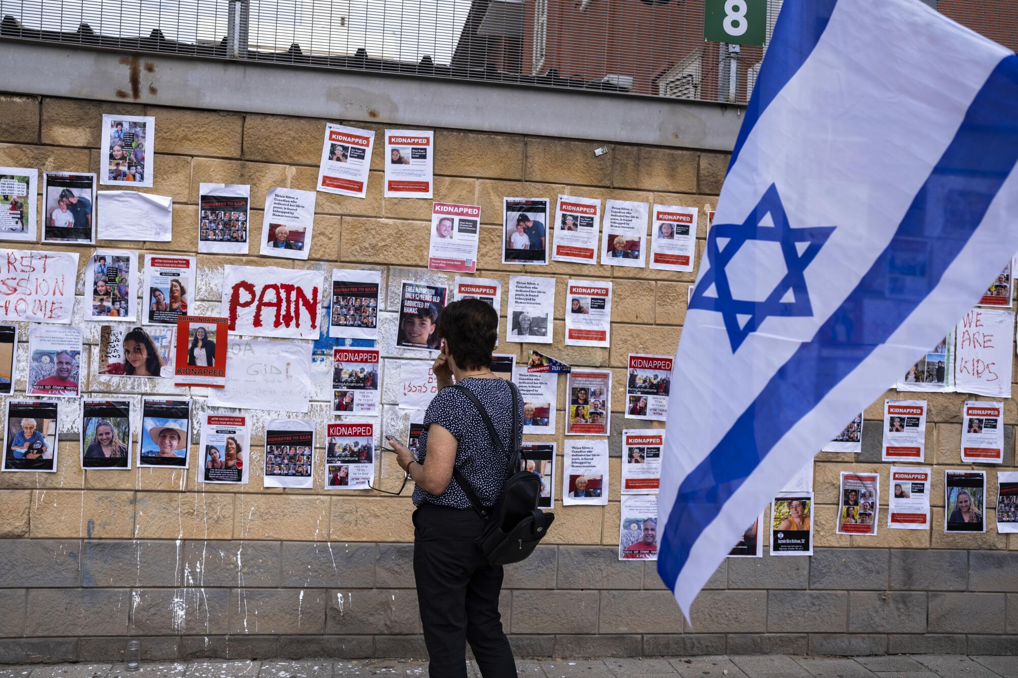 Woman looking at wall with photos of Israelis being held captive in Gaza