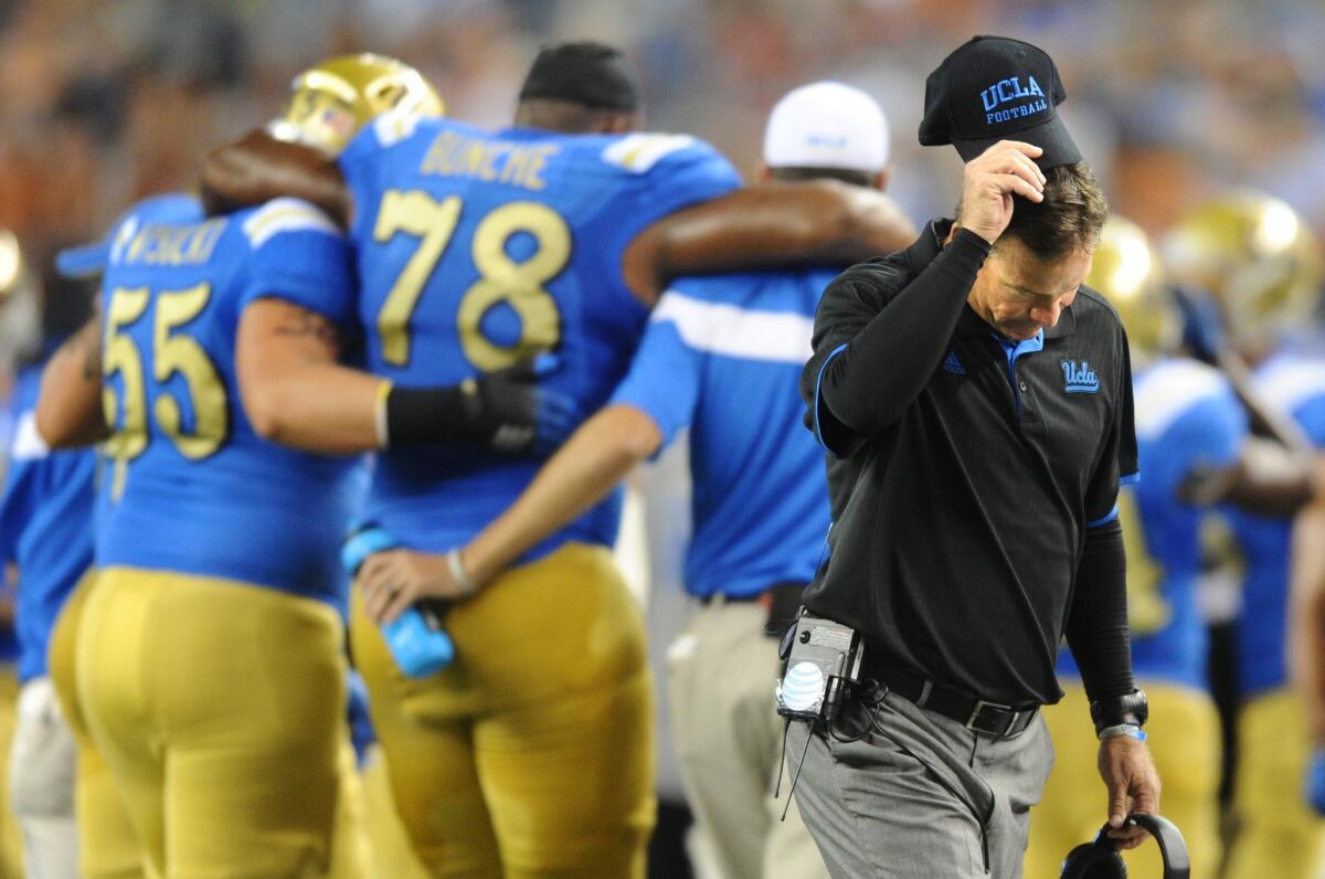 A frustrated UCLA Coach Jim Mora walks away as lineman Malcolm Bynche is carried off the field during an injury timeout.