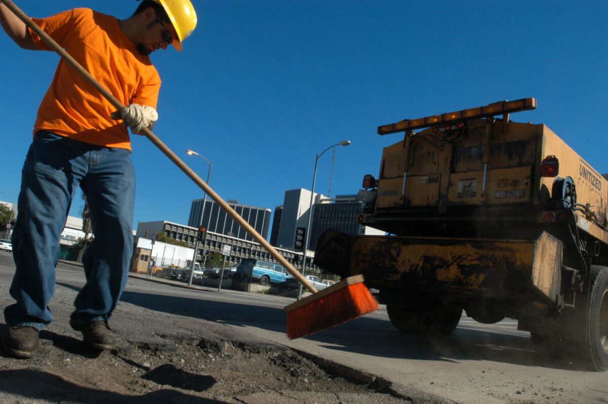 Ozzie Haro prepares a pot hole to be filled in 2005. Since 2005, the city has paid for normal upkeep and maintenance on streets of good quality, but has left a backlog of severely damaged roads largely untouched.
