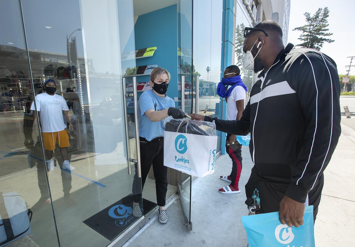 Customers do curbside pickup at Cookies, a streetwear clothing store on Melrose Avenue in Los Angeles. 